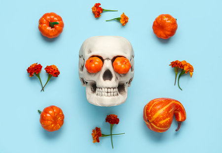 Human skull with marigold flowers and pumpkins on blue backgroundの写真素材