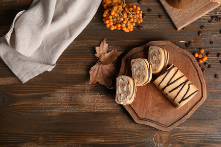 Board with sweet cut sponge cake roll and rowan on wooden backgroundの写真素材