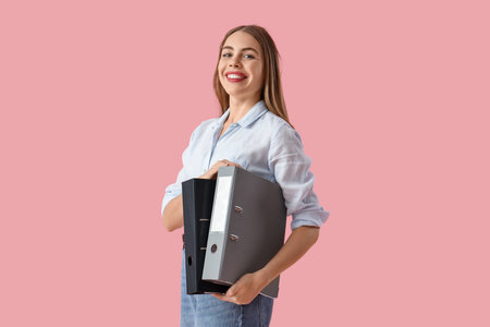 Young businesswoman with document folders on pink background