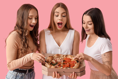 Female friends with tasty pizza on pink backgroundの写真素材