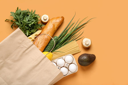 Paper shopping bag with different fresh products on orange backgroundの写真素材