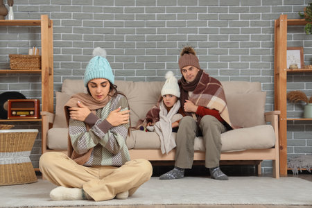 Frozen family in warm clothes at home with lack of heatingの写真素材