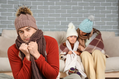 Frozen family in warm clothes at home with lack of heatingの写真素材