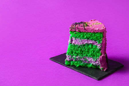 Piece of tasty Halloween cake with spider on purple background, closeupの写真素材