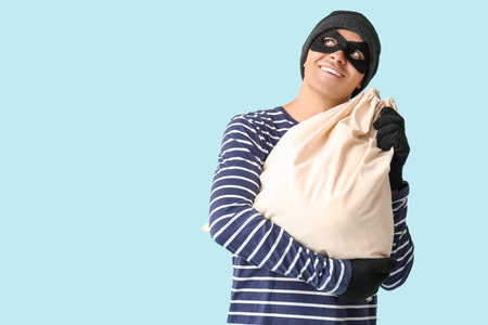 Male thief with bag on blue backgroundの写真素材