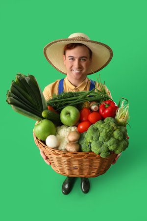 Male farmer with fresh vegetables on green backgroundの写真素材