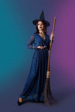 Young witch with crystal ball and broom on dark color backgroundの写真素材