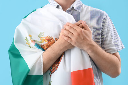 Young man with Mexican flag on blue background, closeupの写真素材