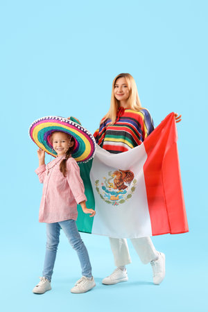 Little girl with her mother and Mexican flag on blue backgroundの写真素材