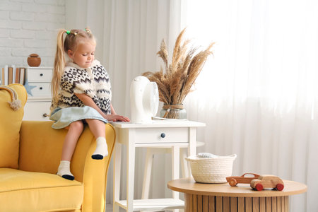 Cute little girl with electric fan heater at homeの写真素材