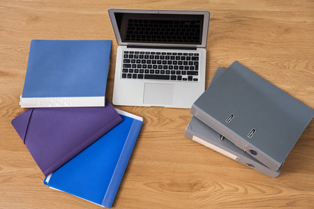 Laptop with document folders on table in office, top viewの写真素材