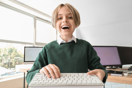 Little boy with keyboard at school computer lab