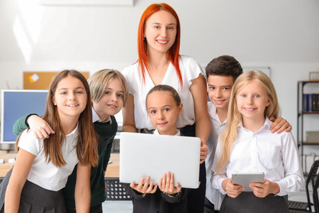 Little children with laptop and teacher at school computer labの写真素材