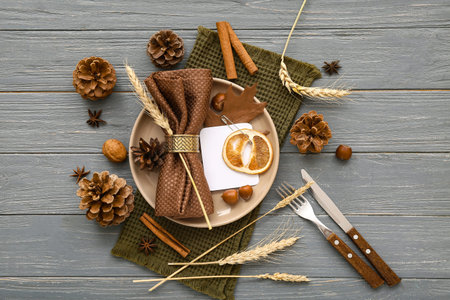 Autumn table setting with wheat spikelets, spices and cones on gray wooden background