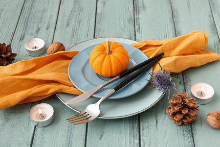 Autumn table setting with pumpkin, dried flower and burning candles on blue wooden backgroundの写真素材