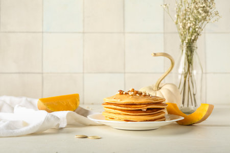 Plate of tasty pumpkin pancakes with honey and nuts on white wooden tableの写真素材