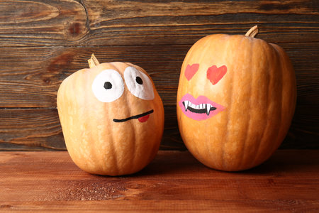 Funny Halloween pumpkins with drawn faces on wooden backgroundの写真素材