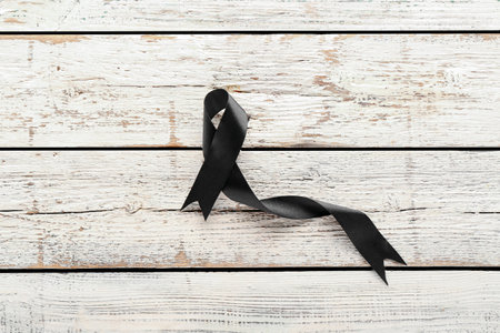 Black funeral ribbon on white wooden backgroundの写真素材