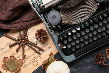 Vintage typewriter, pine cones, rings, music notes, keys and autumn leaves on black backgroundの写真素材
