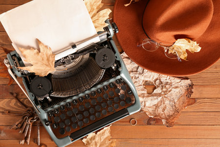Vintage typewriter, rings, hat, eyeglasses, keys, map and autumn leaves on wooden backgroundの写真素材