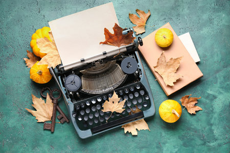 Vintage typewriter, pumpkins, keys, book and autumn leaves on green backgroundの写真素材