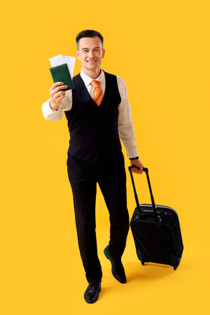Handsome steward with passport and suitcase on yellow backgroundの写真素材