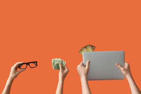 Women with credit cards, eyeglasses, cash and laptop on orange background