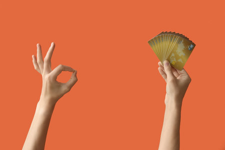 Woman with credit cards showing OK on orange backgroundの写真素材