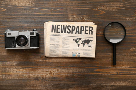 Morning newspaper, magnifying glass and photo camera on wooden backgroundの写真素材