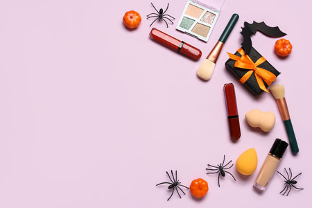 Gift box and different decorative cosmetics with Halloween decor on pink backgroundの写真素材