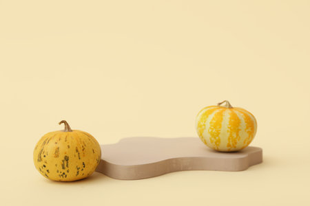 Plaster podium with pumpkins on light yellow backgroundの写真素材