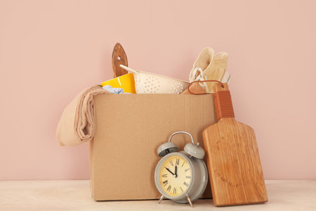 Box of unwanted stuff for yard sale on table near pink wall