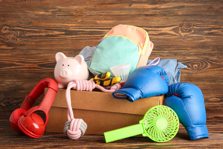 Box of unwanted stuff for yard sale on brown wooden background