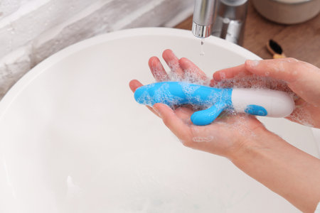 Woman washing vibrator over sink, closeupの写真素材