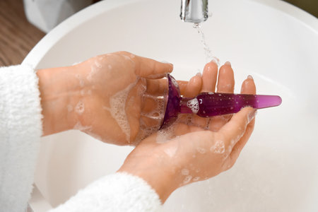Woman washing anal plug over sink, closeupの写真素材