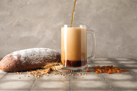 Pouring of tasty kvass into mug on tableの写真素材