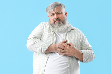 Senior man having heart attack on blue backgroundの写真素材