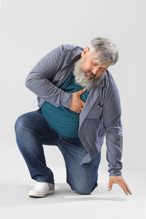 Senior man having heart attack on light backgroundの写真素材