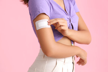 Young woman with birth control patch on pink background, closeup