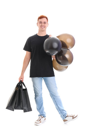 Happy young redhead man with shopping bags and balloons isolated on white background. Black Friday saleの写真素材