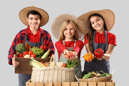 Little farmers with fresh food at counter on light backgroundの写真素材