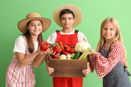 Little farmers with fresh food on green backgroundの写真素材