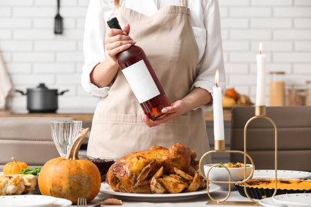 Woman with bottle of wine at dining table set for Thanksgiving Day, closeupの写真素材