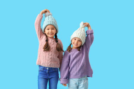 Cute little girls in warm clothes on blue backgroundの写真素材