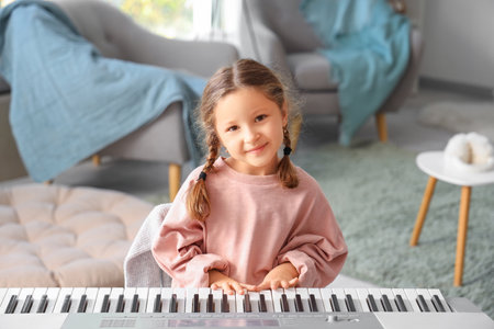 Cute little girl playing synthesizer at homeの写真素材