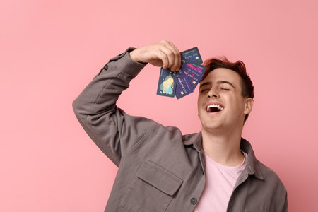 Young man with credit cards on pink backgroundの写真素材