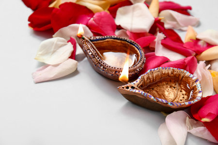 Diya lamps with beautiful flower petals on gray background. Divaly celebration