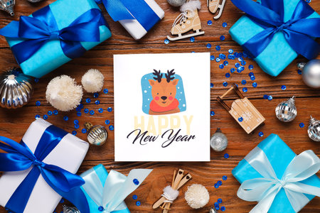 Beautiful Christmas composition with greeting card, decor and gift boxes on wooden backgroundの写真素材