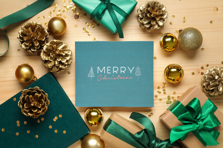 Greeting card with text MERRY CHRISTMAS, gift boxes and decor on wooden backgroundの写真素材