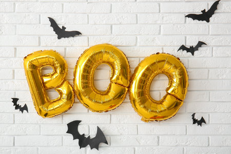 Text BOO made of balloons and paper bats hanging on light brick wallの写真素材